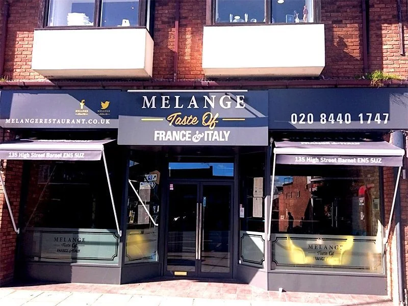 Branded fabric awnings above the windows and entrance of a brick storefront