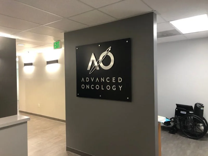 Dimensional medical practice logo on a dark reception wall