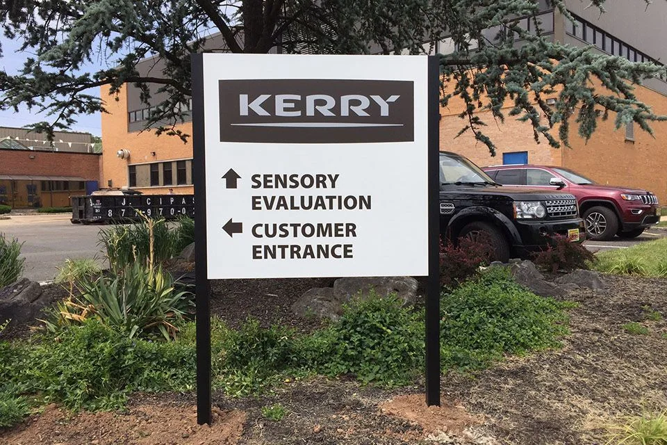 Business identification and entrance directions on a white post-and-panel sign