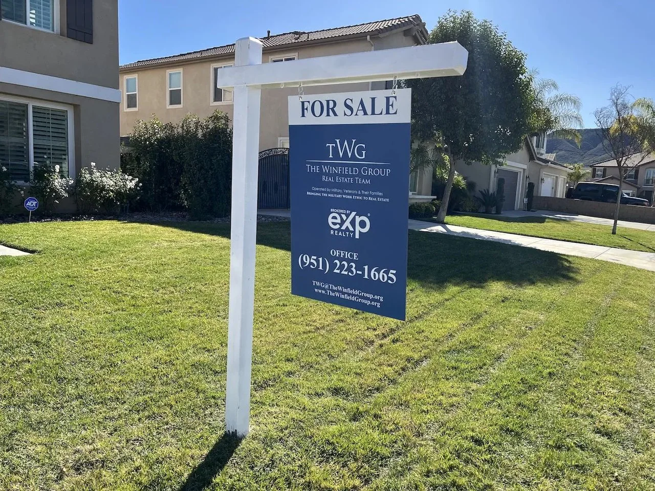 Property listing sign suspended from a white real estate post